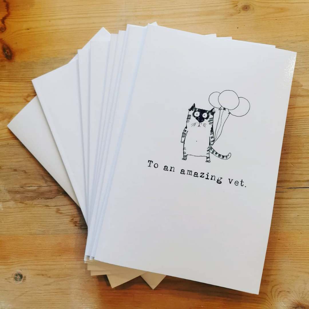 Fanned stack of To an amazing vet gift books for veterinary professionals, the top cover showing an ink cat with balloons