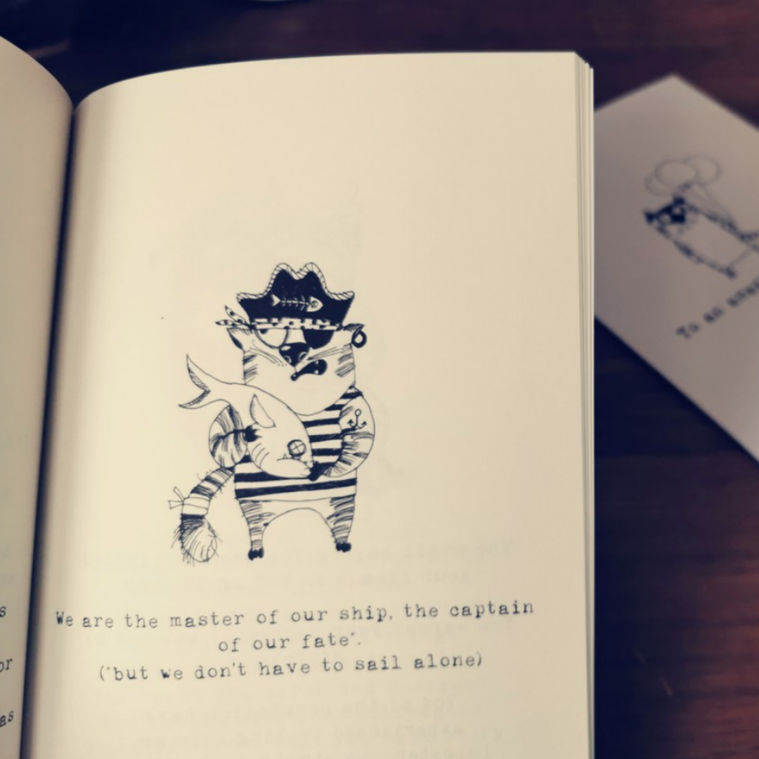 Open page of the vet nurse gift book showing a hand-drawn pirate cat holding a fish with typewriter text